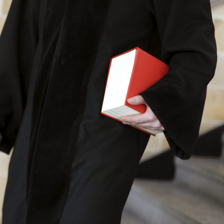 Anwalt mit Robe und Gesetzestext unterm Arm